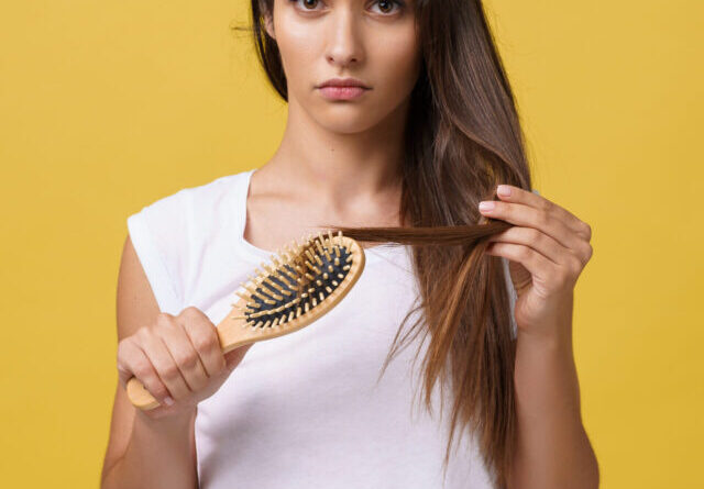 Woman hand holding her long hair with looking at damaged splitting ends of hair care problems.